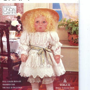 Puede incluir: Un patrón de muñeca Vogue Craft, número 416, que presenta una muñeca con sombrero de paja, cabello rubio rizado y un vestido de encaje blanco. La muñeca tiene una cara pintada y usa calcetines y zapatos blancos. El patrón incluye una transferencia termoadhesiva a color para la cara.