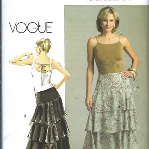May include: A Vogue sewing pattern envelope V8256 for a tiered skirt. The front shows a photograph of a person wearing a light blue and brown paisley print tiered skirt with a tan tank top, and an illustration of a black tiered skirt with a white top.