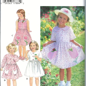 Puede incluir: Patrón de costura Simplicity número 9523 para vestidos de niña. El patrón incluye cuatro estilos diferentes: un vestido blanco con cuello Peter Pan, un vestido de cuadros rosa y blanco con cuello Peter Pan, un vestido blanco con cuello Peter Pan y un bolsillo rosa, y un vestido floral rosa y blanco con cuello Peter Pan y dos bolsillos rosas.