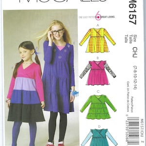 May include: Sewing pattern for a girls' dress with six different looks. The pattern includes a wrap dress with long sleeves and a tiered skirt. The pattern is available in sizes 7-8, 10, 12, and 14. The pattern is called McCall's M6157.