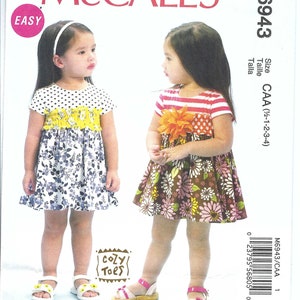 Può includere: Un cartamodello per due vestiti da bambina. Il cartamodello si chiama McCall's M6943 ed è per le taglie 1/2-1-2-3-4. I vestiti sono entrambi a stampa floreale e hanno una gonna a balze. Un vestito ha un corpetto a pois neri e bianchi e l'altro ha un corpetto a righe rosse e bianche.