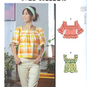 Könnte beinhalten: Ein Schnittmuster für eine Bluse mit mehreren Ansichtsoptionen. Das Schnittmuster enthält Anleitungen zum Nähen einer karierten Bluse, einer rosa Bluse mit Rüschen und einer Blusen mit Blumenmuster und Rüschen. Das Schnittmuster ist für die Größen XS, S und M.