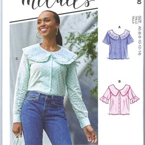 May include: A sewing pattern for a collared blouse with ruffle details. The pattern includes three different views: a light blue blouse with white polka dots, a pink and white striped blouse, and a lavender blouse with white polka dots. The pattern is for sizes 6-8-10-12-14. The pattern includes the hashtag #MalloryMcCalls.