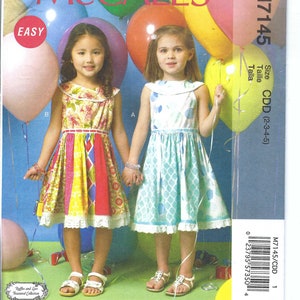 Può includere: Un cartamodello per due vestiti da bambina. Il cartamodello si chiama McCall's M7145 ed è per le taglie 2-3-4-5. I vestiti sono entrambi senza maniche e hanno un colletto alla Peter Pan. Un vestito è blu con pois bianchi e l'altro è multicolore con un design patchwork.