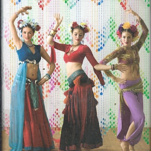 Puede incluir: Patrón de costura Simplicity para disfraces de baile. La imagen muestra a tres bailarinas con trajes de danza del vientre coloridos. Los disfraces incluyen tops cortos, faldas y pantalones en tonos de azul, rojo y morado. El texto "the dance studio" es visible.