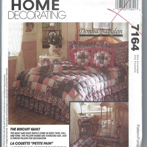 May include: A sewing pattern for a quilt and pillow shams. The pattern is called "The Biscuit Quilt" and "Petite Pain". The quilt is pink, green, and white with a ruffled edge. The pillow shams are also pink, green, and white. The pattern is from McCall's Home Decorating.