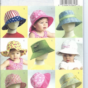 May include: Butterick B5056 sewing pattern featuring various baby and toddler sun hats. The hats include designs with stars and stripes, floral prints, and solid colors. The pattern includes all sizes.