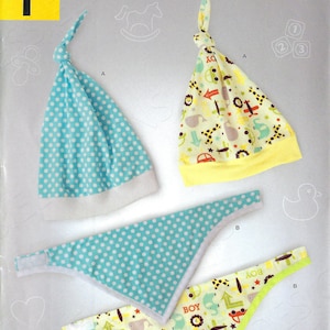 Könnte beinhalten: Ein Nähmuster für eine Baby-Mütze und ein Lätzchen. Das Muster enthält zwei verschiedene Designs, eines mit blauen Punkten und das andere mit gelbem Hintergrund und einem bunten Druck von Tieren und Fahrzeugen. Das Muster heißt "IT'S SO EASY" und stammt von Simplicity.