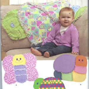 May include: Simplicity pattern 1822 featuring stuffed animal designs. The pattern includes a butterfly, snail, and turtle. The image shows a baby sitting on a pillow shaped like a caterpillar. The pattern is one size.