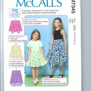 Puede incluir: Patrón de costura McCall's para faldas para principiantes. El patrón incluye ilustraciones de varios diseños de faldas, incluyendo una falda rosa con lunares, una falda floral y una falda morada. Diseñado e impreso en EE. UU.