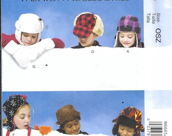 May include: McCall's Fashion Accessories pattern featuring six different hat designs. The hats include a white bear-style hat, a red and black plaid hat, a purple plaid hat, a black knit hat, a brown hat, and a red and yellow flame-patterned hat.