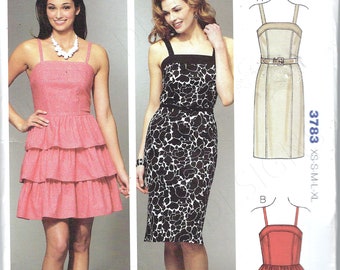 May include: Kwik Sew pattern 3783 for misses' dresses. The pattern includes a pink tiered dress, a black and white floral print dress, and line drawings of the dress designs. Sizes XS-XL are available.