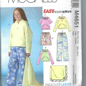 May include: A sewing pattern for a girls' fleece pajama set. The pattern includes a hooded top, pants, and a blanket. The pattern is for sizes 8-16. The pattern is called "Fabulous Fleece" and is from McCall's.