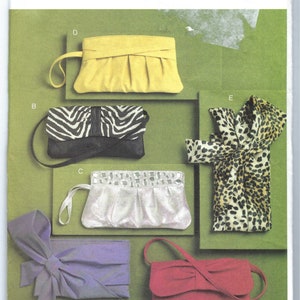 May include: Vogue Accessories V8527 sewing pattern envelope featuring illustrations of five different clutch bags and purses in yellow, zebra print, silver, leopard print, purple with a large bow, and a solid red with a shoulder strap.