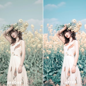 May include: A woman in a white dress with a floral pattern stands in a field of yellow flowers. She is holding a bouquet of white flowers above her head. The background is a blue sky.