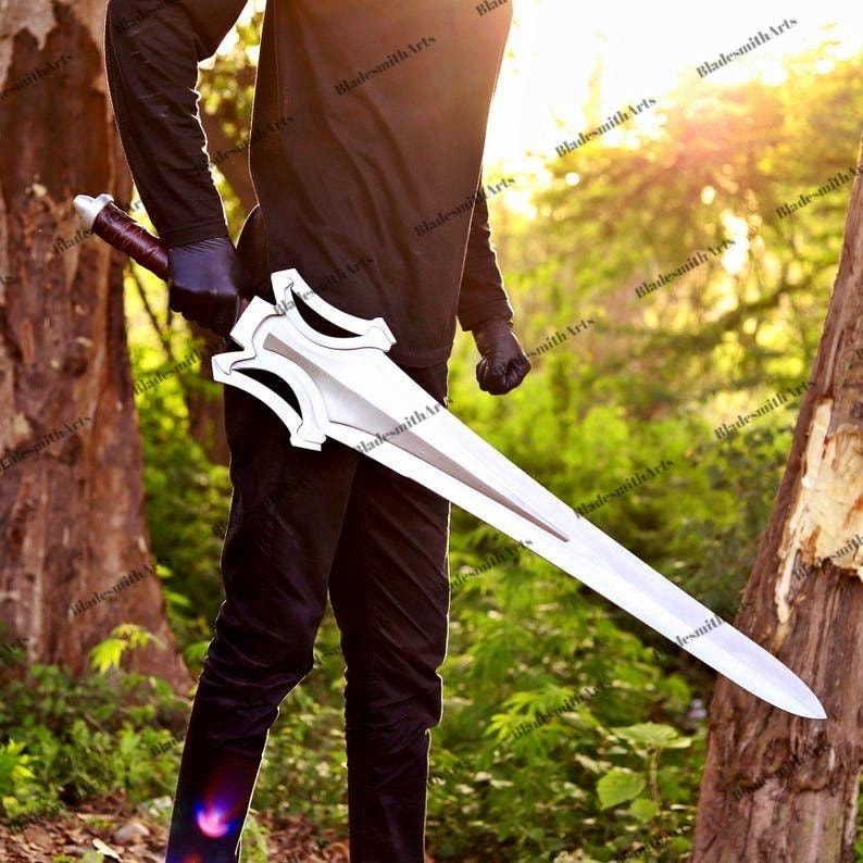 May include: A long, silver-colored sword with a pointed tip and a complex, angular crossguard. The handle is wrapped in dark brown material. The blade features a central ridge and a symmetrical design, held horizontally against a dark-clad torso.