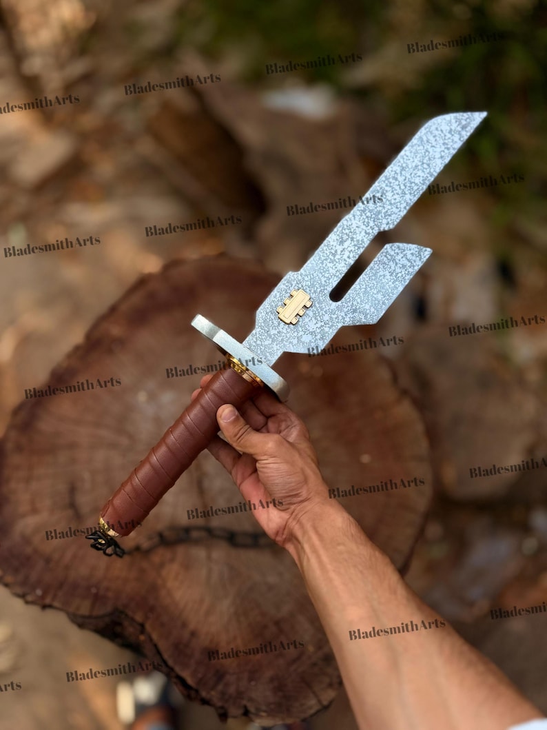 May include: A metal sword with a textured, silver-colored blade featuring a rectangular cutout and a gold-colored emblem. The handle is wrapped in brown leather, and a small black chain is attached to the pommel at the base of the grip.