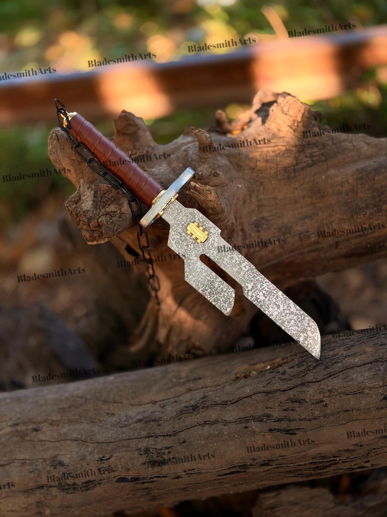 May include: A decorative dagger with a brown leather-wrapped handle and a silver blade. The blade has a unique cutout design and a gold-colored emblem. A chain is attached to the handle. The dagger is displayed on a piece of wood.