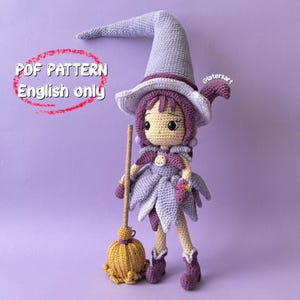 May include: A crochet doll featuring a light purple pointed hat, dark purple hair, and a matching dress with petal-like layers. The doll holds a yellow broom and has a small button on the chest. Text on the image reads: PDF PATTERN English only.