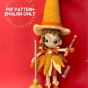 May include: A crocheted doll dressed as a witch with a tall orange hat, brown hair, and round glasses. The doll wears a layered skirt of orange and yellow leaf-shaped pieces, holds a broom, and a wand with colorful beads. Text reads PDF PATTERN ENGLISH ONLY.