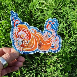 May include: A colorful sticker featuring an orange and blue octopus with white and red details. The octopus is drawn in a batik style with a swirling pattern.