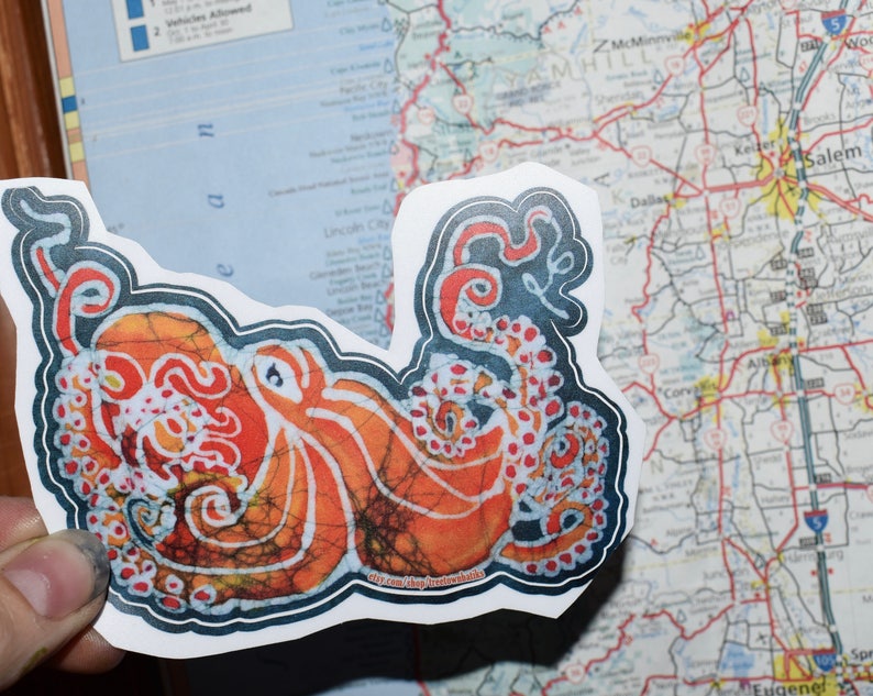 May include: A sticker featuring a colorful octopus with a batik pattern. The octopus is orange, red, and white with black outlines. The sticker is on a white background.