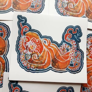 May include: Orange and blue octopus sticker with a batik design. The octopus is outlined in blue and has a white background.