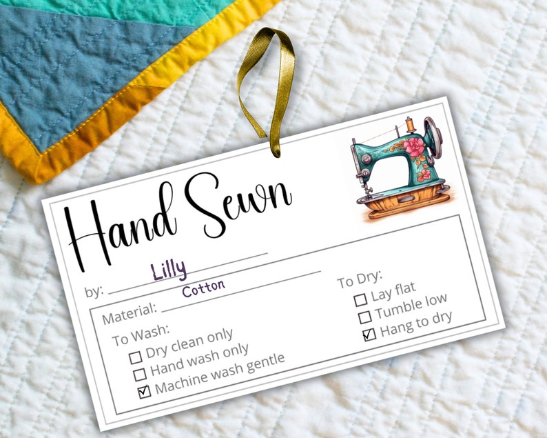 May include: A white tag with the text "Hand Sewn" in cursive script. The tag also includes the text "by: Lilly Cotton" and a list of care instructions for the item. The tag features a cartoon illustration of a sewing machine with a floral design.