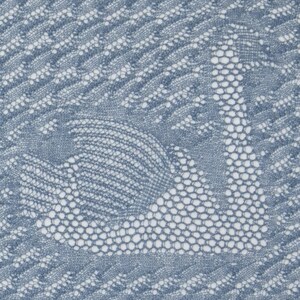 May include: Close-up of a blue and white knitted textile featuring a swan design. The swan is created with a detailed openwork pattern, with the body and neck in a solid blue, and the surrounding areas in a white, open weave.