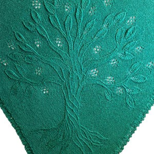 Könnte beinhalten: Smaragdgrünes Textil mit einem gestickten Baumdesign. Der Baum hat detaillierte Blätter und kleine Blumenakzente. Der Stoff hat ein strukturiertes Aussehen und die Kanten sind mit einer dekorativen Bordüre versehen. Das Design ist auf dem Textil zentriert.