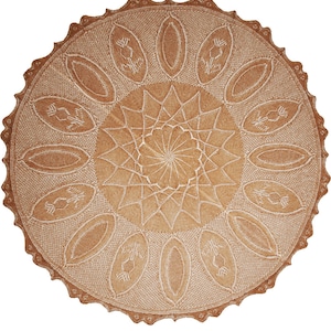 May include: A round, tan-colored doily with an intricate, symmetrical design. The center features a starburst pattern, surrounded by oval shapes with floral motifs. The edge has a scalloped border, adding a decorative touch to this handcrafted textile.