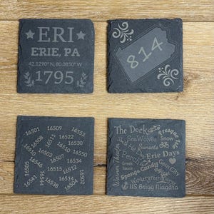 Op de afbeelding: Vier vierkante leistenen onderzetters met gegraveerde ontwerpen. Eén onderzetter toont "ERI, ERIE, PA, 1795" met coördinaten. Een andere toont "814" binnen een staatsomtrek. De anderen hebben postcodes en lokale bezienswaardigheden.