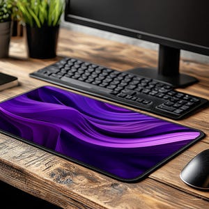 May include: Purple and black abstract design mousepad with a wavy pattern. The mousepad is on a wooden desk with a keyboard and a computer monitor.