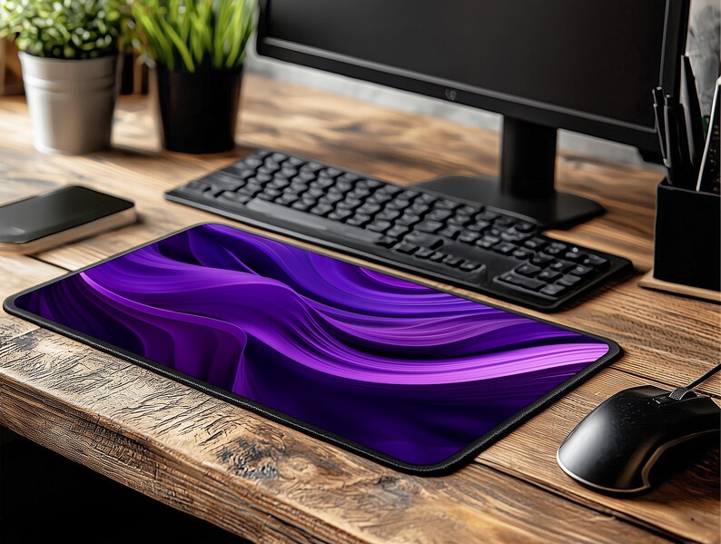 May include: Purple and black abstract design mousepad with a wavy pattern. The mousepad is on a wooden desk with a keyboard and a computer monitor.