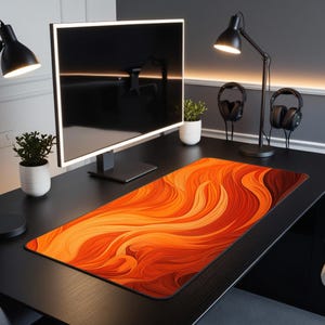 May include: A black computer desk with a large monitor, two lamps, and a pair of headphones. A large orange and red abstract design mousepad is on the desk.