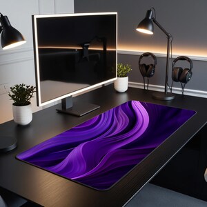 May include: A purple and black abstract design mousepad with a wavy pattern. The mousepad is on a black desk with a computer monitor, two lamps, and two headphones.