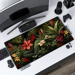 Könnte beinhalten: Eine große Mausmatte in Schwarz und Grün mit tropischem Blumenmuster. Das Design zeigt große grüne Blätter, rote und weiße Blüten und eine Vielzahl anderer tropischer Pflanzen.
