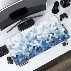 Puede incluir: Alfombrilla de escritorio rectangular con un diseño pixelado en tonos azules y blancos. La alfombrilla está rodeada de accesorios informáticos, como un monitor curvo, un teclado, un ratón y un altavoz. La alfombrilla de escritorio mide unos 91 cm de largo.