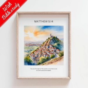 Puede incluir: Una pintura de acuarela de una ciudad en una colina con un sol brillante en el cielo. La pintura está enmarcada en un marco de madera claro. El texto "MATTHEW 5:14" está impreso en la parte superior de la pintura. El texto "Ustedes son la luz del mundo. Una ciudad que está situada en una colina no puede ser escondida." está impreso en la parte inferior de la pintura.