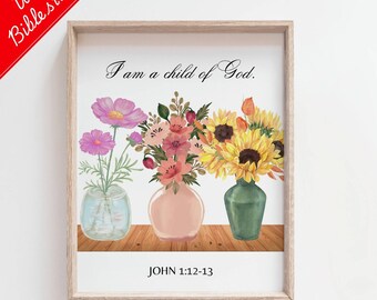 May include: A framed print featuring watercolor illustrations of flowers in vases. The text "I am a child of God" is above the flowers, with "JOHN 1:12-13" below. The frame is light brown, and the image has a red banner that says "With Bible study".