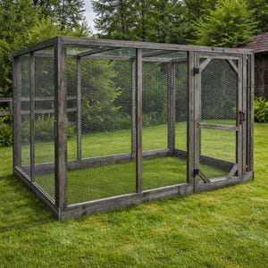 Könnte beinhalten: Ein großer, rechteckiger Hühnerstall aus Holz mit grauer Oberfläche. Der Stall hat Seiten aus Drahtgeflecht und eine Tür. Er steht auf einer Rasenfläche mit Bäumen im Hintergrund.