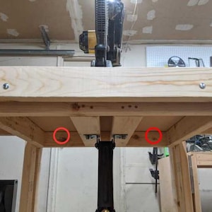 May include: A wooden table with two red circles highlighting the underside of the table where the legs are attached.