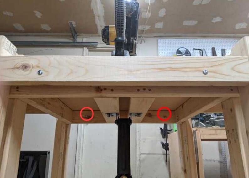 May include: A wooden table with two red circles highlighting the underside of the table where the legs are attached.