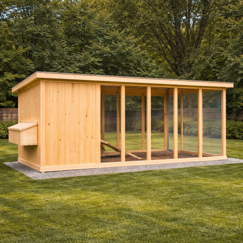 May include: A large, rectangular wooden chicken coop with a nesting box and a screened-in run. The coop is constructed from light-colored wood and sits on a gravel base, with a green lawn in the foreground and trees in the background.