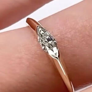 Könnte beinhalten: Ein zarter Goldring mit einem einzigen, mittig gesetzten Diamanten in Marquise-Form.
