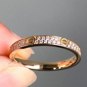 Könnte beinhalten: Ein Goldring mit einer Reihe kleiner Diamanten und zwei gravierten Kreisen auf der Oberseite.