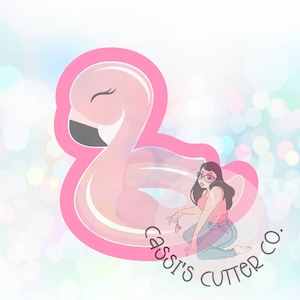 May include: A pink flamingo cookie cutter with a smiling face. The image also features a woman with glasses and the text "Cassi's Cutter Co."