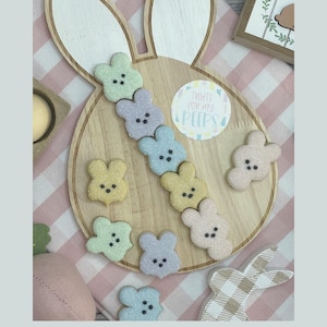May include: A wooden bunny-shaped cutting board with a circle sticker that says "Treats for my peeps" and is decorated with pastel-colored sugar cookies shaped like Peeps.