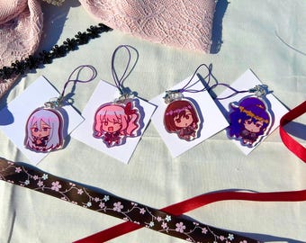 May include: Four colorful anime character keychains with purple, pink, and blue accents. Each keychain features a different character with a unique design and is attached to a string.