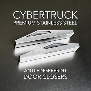 May include: Two silver door closers made of premium stainless steel. The door closers have a unique design with a small cutout in the middle. The text "CYBERTRUCK PREMIUM STAINLESS STEEL ANTI-FINGERPRINT DOOR CLOSERS" is printed below the door closers.